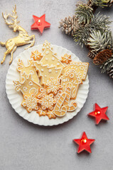 Christmas gingerbread cookies decorated with icing on white plate with festive decorations