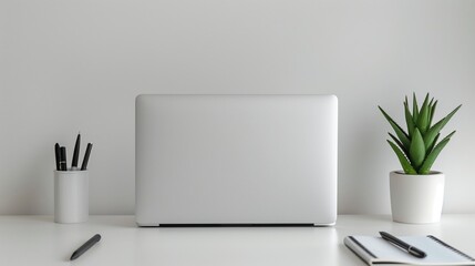 A minimalist desk setup featuring a spotless white desk with a slim, modern laptop placed in the center. To the left, there is a single, elegant pen and a closed notebook with a smooth cover.