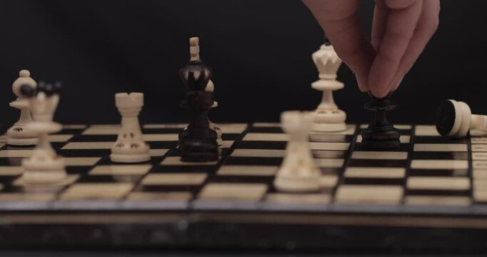 Caucasian man's hand making a move on a chessboard, capturing a white pawn with a black one, 4K