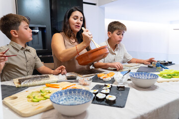 Family preparing sushi rolls at home in the kitchen