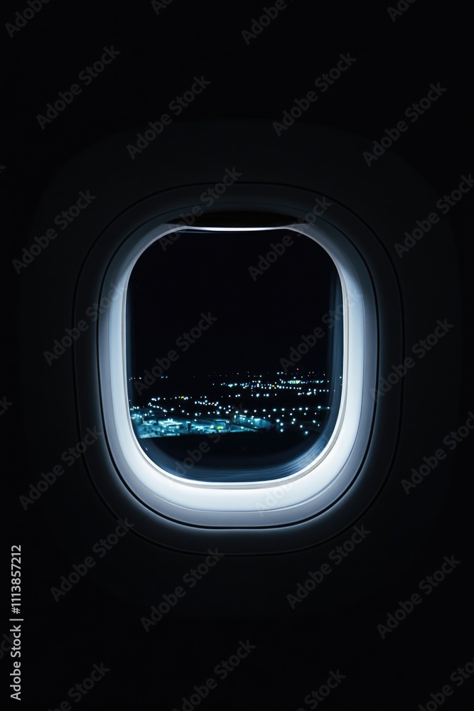 Poster window on an airplane with a city view. the window is open and the view is dark