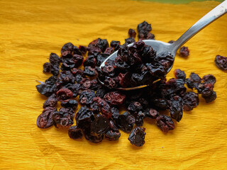 Dried berries on a yellow background in a spoon. Currant.