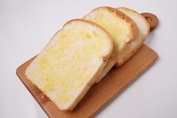 Buttered bread cut into slices on a wooden tray white background