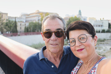 Married and retired couple taking a selfie in front of the Borgia ducal palace, Gandia, Valencia, Spain - Husband and wife enjoying a romantic moment together on summer vacation in Europe.