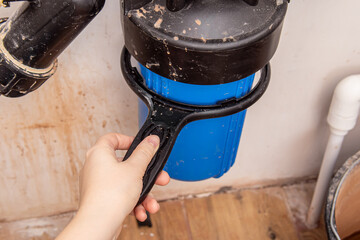 Woman unscrews the filter flask with black plastic key to replace the cartridge