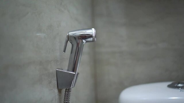 Handheld bidet in bathroom. Close up of chromium bidet shower in a toilet.