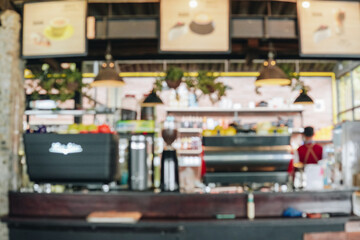 Blurred coffee shop interior, store counter with a menu board and coffee grinding machines.