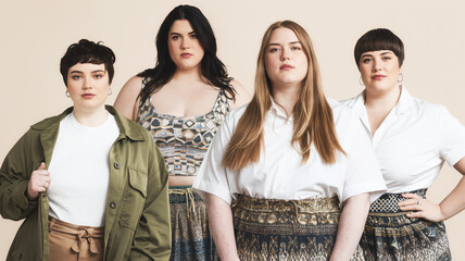 Four plus size models posing together on beige background