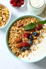 Delicious granola with berries and yogurt on a light background