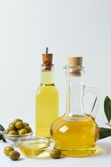 Bottle of fresh olive oil and olives with leaves on the table