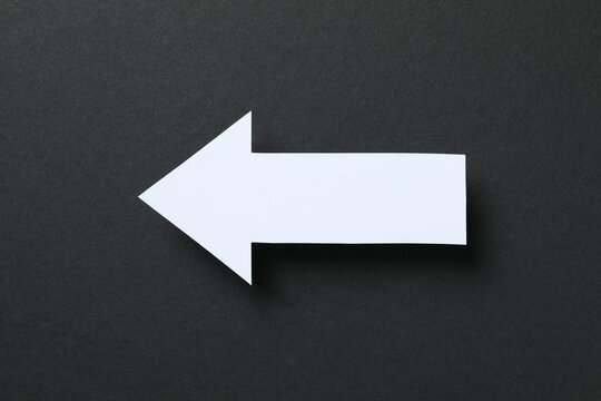 Paper arrow on black background, top view