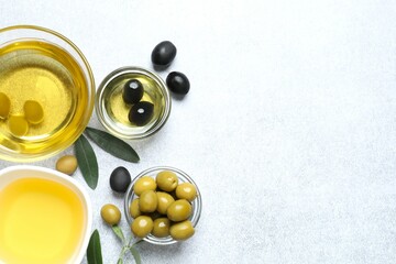Bowl of fresh olive oil and olives with leaves on the table