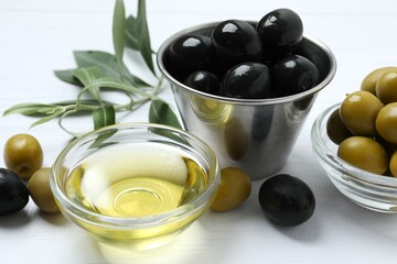 Bowl of fresh olive oil and olives with leaves on the table