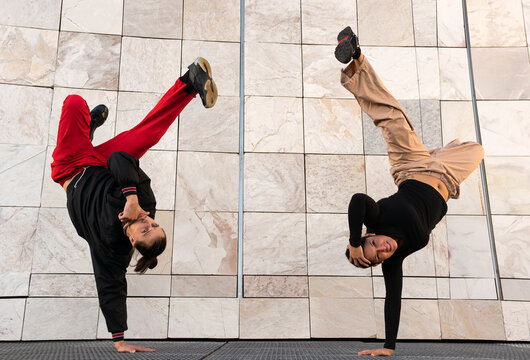 A young man and a young woman breakdancing in the street
