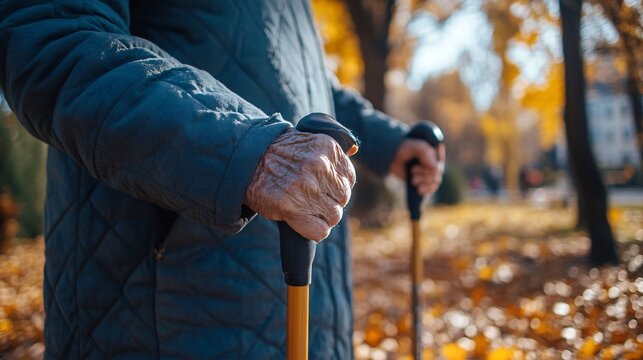 Senior woman holding trekking poles while walking in autumn park