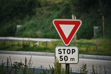 Panneau stop 50m avant une intersection. Panneau de signalisation de danger. Sécurité routière