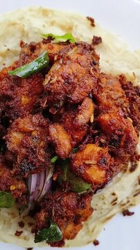 Popular Kerala or malabari south indian dish maida flour porotta, paratha or roti with spicy fried chicken 65 curry on plate. Beautiful Indian food closeup macro Top view.