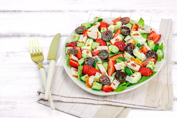 Fresh salad with strawberry, leaves mix, brie cheese, ripe grape and smoked chicken