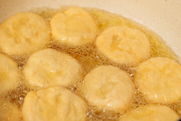 Golden-brown dough balls frying in hot oil, bubbling and sizzling.