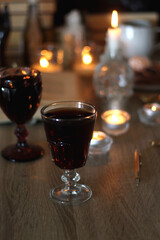 Books, lit candles, red wine, snacks and various deocration on the table. Dark academia or Halloween concept. Selective focus.