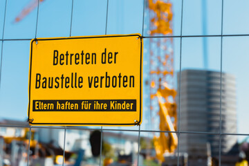 Ein gelbes Schild an einem Zaun hängend mit der Schrift 