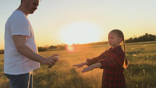 Father protect child with spray against mosquitoes, midges. Man dad spray on child kid daughter protect skin body from bites of mosquitoes, midges. Necessary measures for comfortable pastime in nature