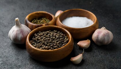 Dark background culinary image featuring wooden bowls of peppercorns and garlic cloves 
