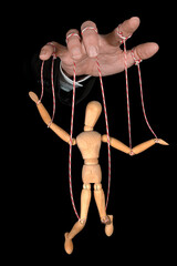 Wooden puppet doll, obeying master  hand pulling the strings of dancing marionette