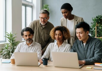 Fototapeta premium Businesspeople working together on laptops, demonstrating teamwork and diversity in a contemporary office setting