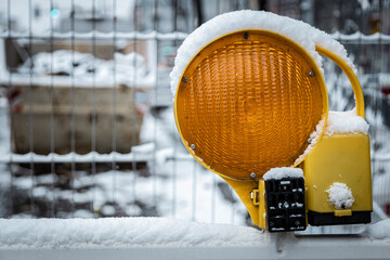 Eine mit Schnee bedeckte Baustellenleuchte auf einer Winterbaustelle