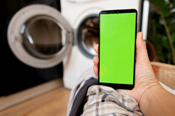 A woman's hand holds a phone with a green screen, remote control of home appliances through...