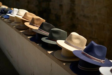 Assortment of stylish hats neatly aligned on a ledge under warm lighting, Portugal