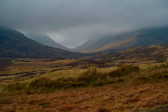 A misty mountain peak with its summit shrouded by low-hanging clouds, set against a somber sky, Scotland