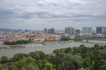 Fototapeta premium Cityscape of Bratislava featuring the Danube River, urban skyline, and iconic green bridge.