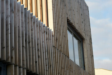 Modern architecture detail showing vertical louvers and a large window on a building facade under a clear sky, Berlin, Germany