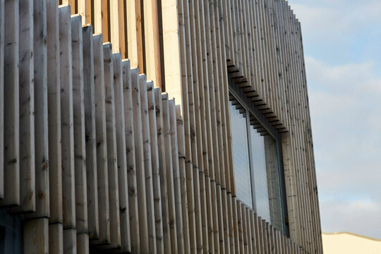 Modern architecture detail showing vertical louvers and a large window on a building facade under a clear sky, Berlin, Germany