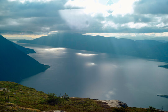 Sun rays breaking through the clouds over a serene Norwegian Fjord, Romsdalfjorden, Norway
