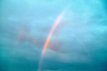 A vibrant rainbow arcs through a cloudy sky, Norway