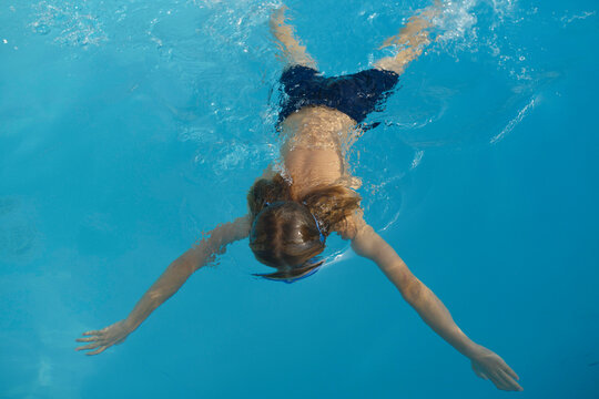 View of a teenager swimming with outstretched arms in a clear blue pool, Pyrenees, France