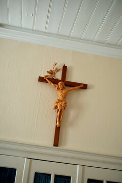 Wooden crucifix with a figure of Jesus mounted on a white wall under a ceiling with beams, Moselle River, Germany