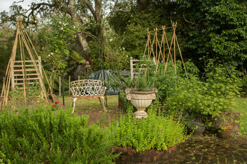 Lush garden scene with a classic stone urn planter surrounded by vibrant greenery and rustic wooden trellises, Auckland, New Zealand