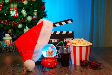 Merry Christmas and New Year Holidays Scene. Santa Claus Hat, Movie Clapperboard, Christmas Tree, Garland, Neon Lights, Cinema Popcorn, and 3D Glasses. Perfect Setting for Holiday Movie Nights at Home