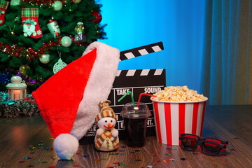 Merry Christmas and New Year Holidays Scene. Santa Claus Hat, Movie Clapperboard, Christmas Tree, Garland, Neon Lights, Cinema Popcorn, and 3D Glasses. Perfect Setting for Holiday Movie Nights at Home