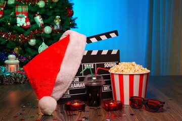 Merry Christmas and New Year Holidays Scene. Santa Claus Hat, Movie Clapperboard, Christmas Tree, Garland, Neon Lights, Cinema Popcorn, and 3D Glasses. Perfect Setting for Holiday Movie Nights at Home