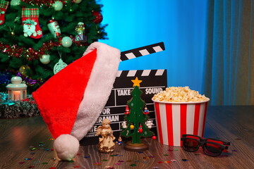 Merry Christmas and New Year Holidays Scene. Santa Claus Hat, Movie Clapperboard, Christmas Tree, Garland, Neon Lights, Cinema Popcorn, and 3D Glasses. Perfect Setting for Holiday Movie Nights at Home