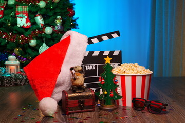 Merry Christmas and New Year Holidays Scene. Santa Claus Hat, Movie Clapperboard, Christmas Tree, Garland, Neon Lights, Cinema Popcorn, and 3D Glasses. Perfect Setting for Holiday Movie Nights at Home