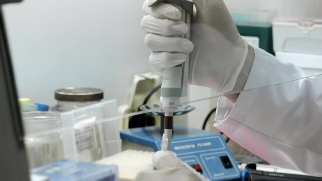 A genetics laboratory researcher drops samples with a pipette. Concept for studying DNA in a modern laboratory. Science and medicine. Lab Experimentation for Genetic Studies.