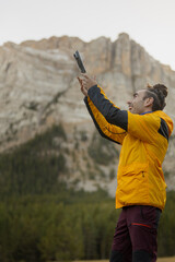 A man in a yellow jacket is taking a picture with a camera