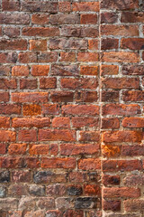 Naklejka premium An old weathered, damaged, badly repaired red brick wall full frame
