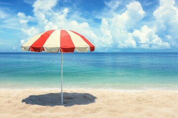 Bright striped beach umbrella provides shade on golden sand under a clear blue sky
